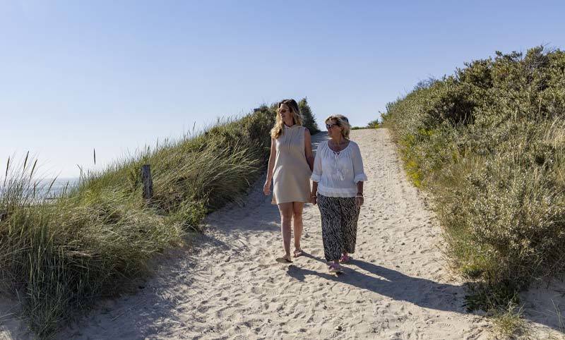 twee vrouwen lopen op de duinen met mooi weer